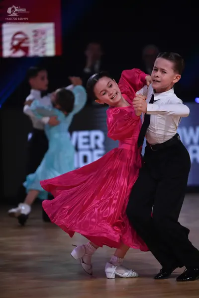 Dancesport competitor: Foreground female dancer: bright pink satin ballgown with long sleeves