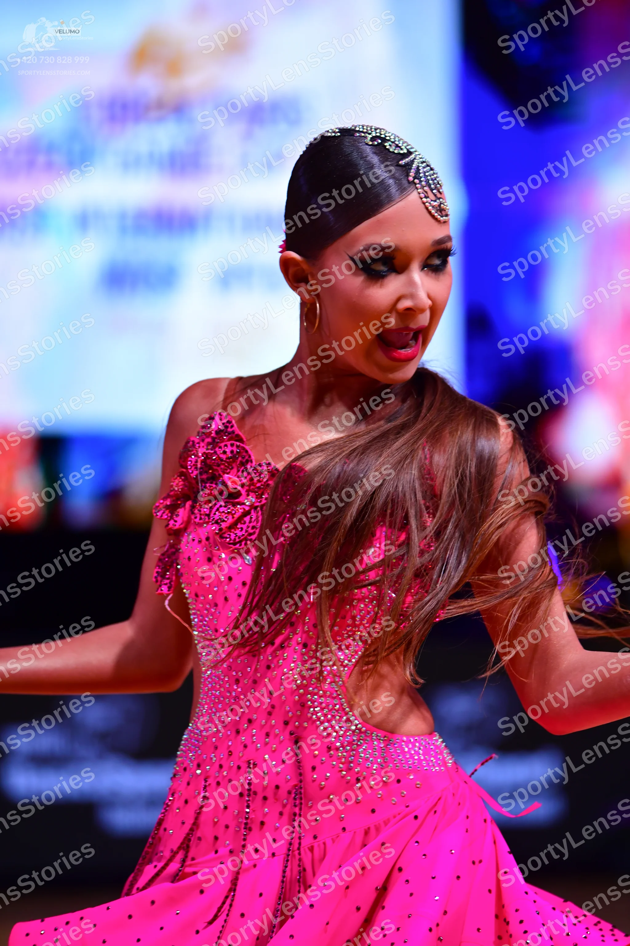 Dancesport competitor: Female dancer: bright pink latin dress with sequins, featuring an asymmetrical s