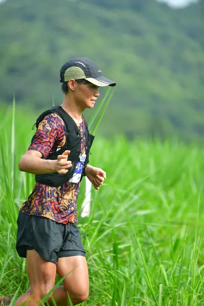 Marathon runner: Runner 1: dark patterned jersey, black shorts, black cap, and black hydration ve