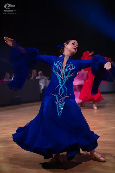 Dancesport competitor: Female dancer in foreground: royal blue ballgown with long, wide bell sleeves an