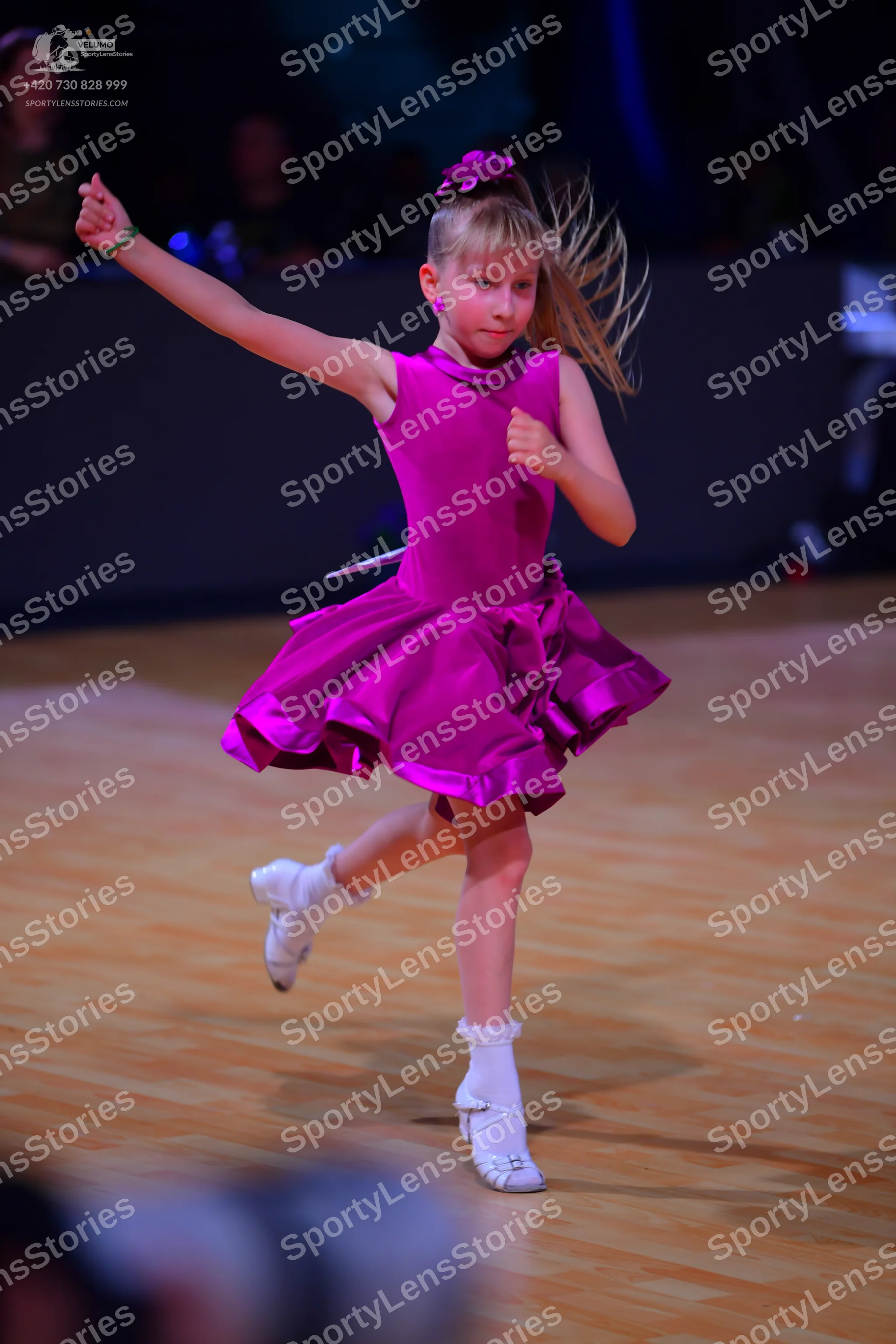 Dancesport competitor: Female dancer: magenta sleeveless dress with a flared, ruffled skirt, a purple f