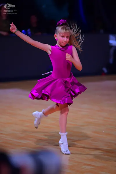 Dancesport competitor: Female dancer: magenta sleeveless dress with a flared, ruffled skirt, a purple f