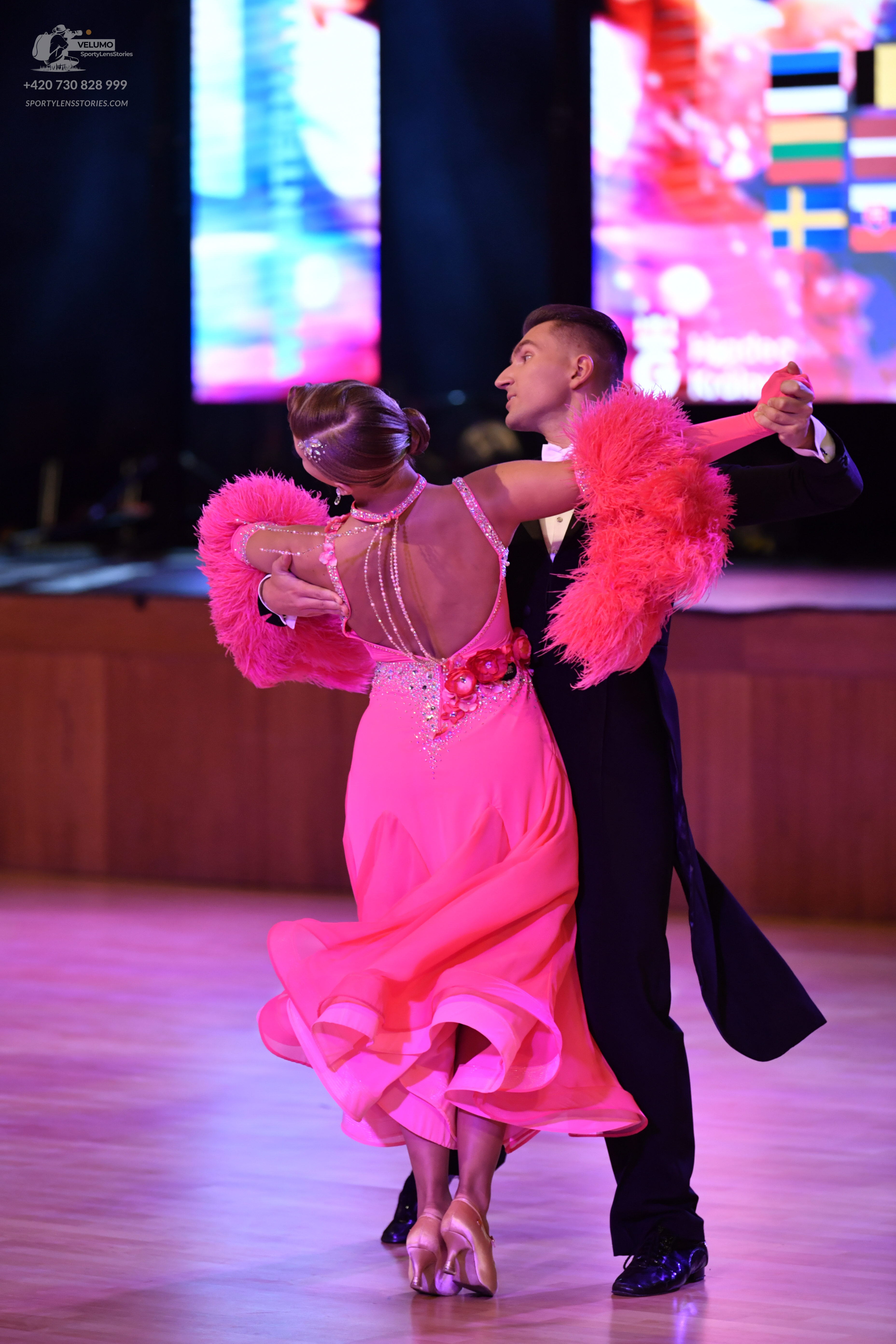 Dancesport competitor: Female dancer: bright pink ballroom dress with large pink feather/fur trim on th