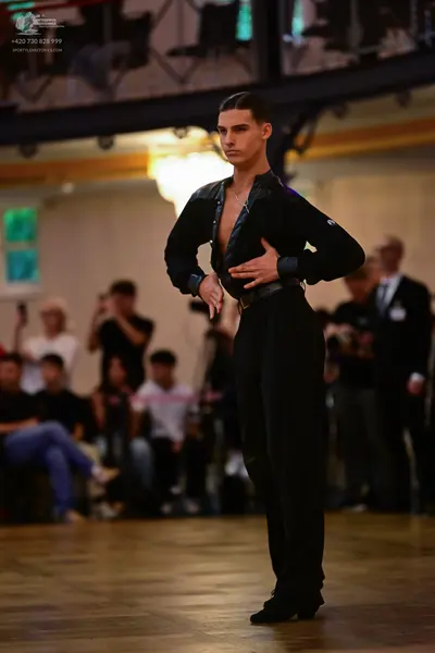 Dancesport competitor: Male dancer: black long-sleeved top, unzipped at the chest, and black trousers