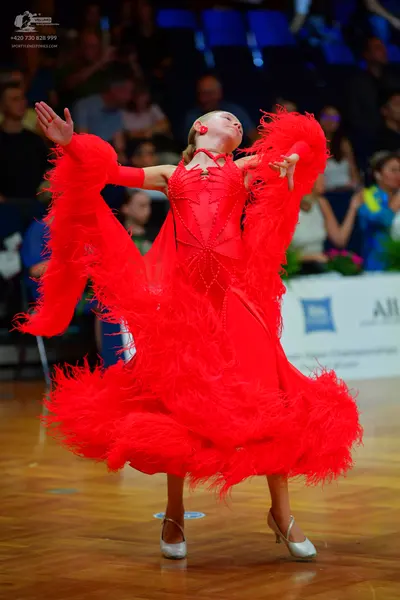 Dancesport competitor: Female dancer: red Latin dress with an extremely voluminous feathery skirt and s