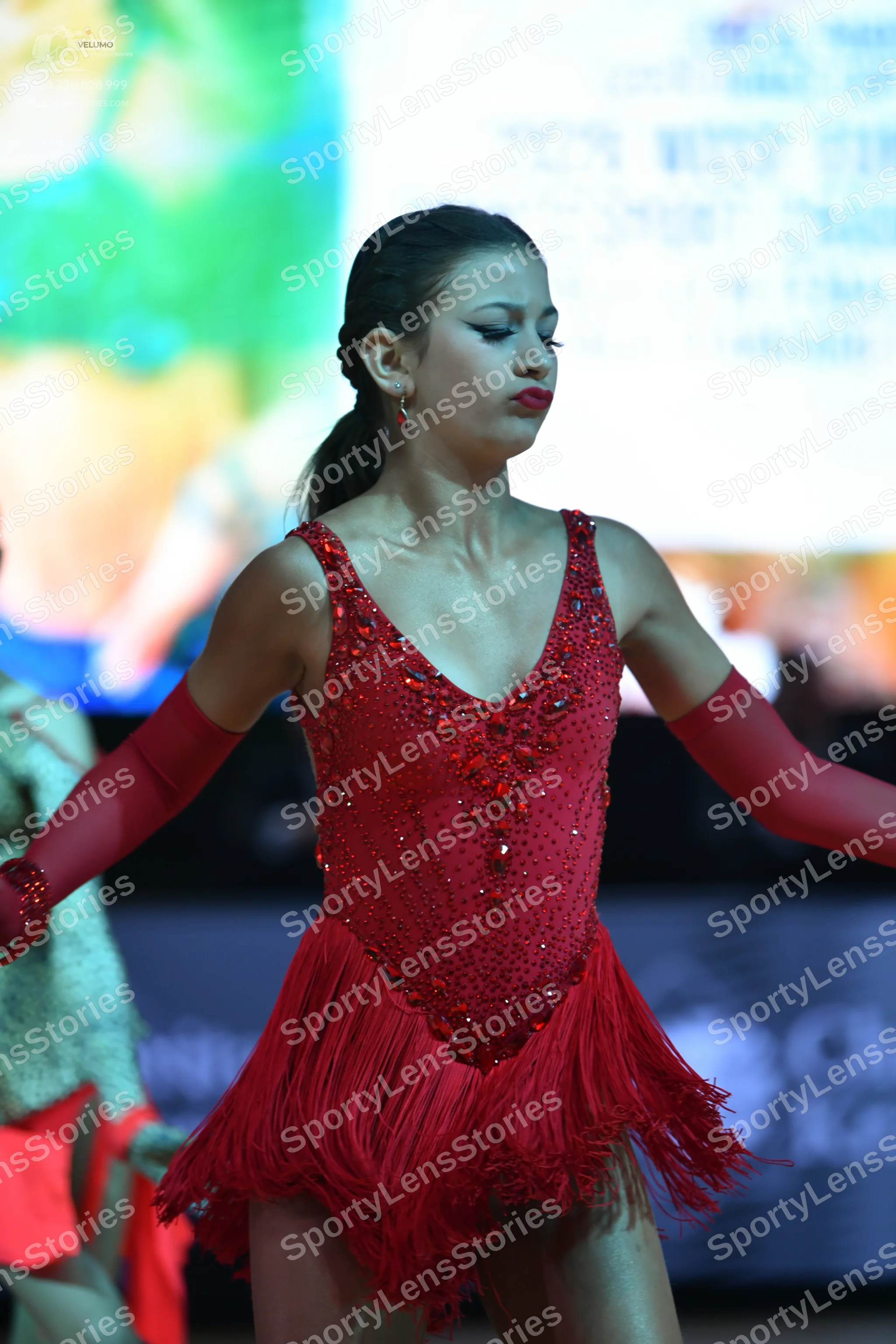 Dancesport competitor: Female dancer: red Latin dress with a sequined bodice and fringe skirt, and long