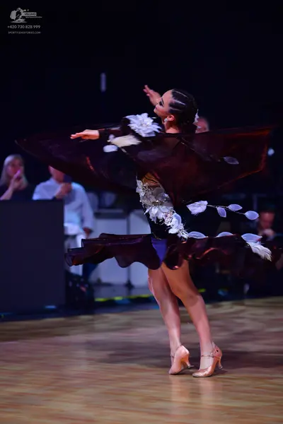 Dancesport competitor: Female dancer: dark burgundy Latin dance dress with large, voluminous, ruffled f