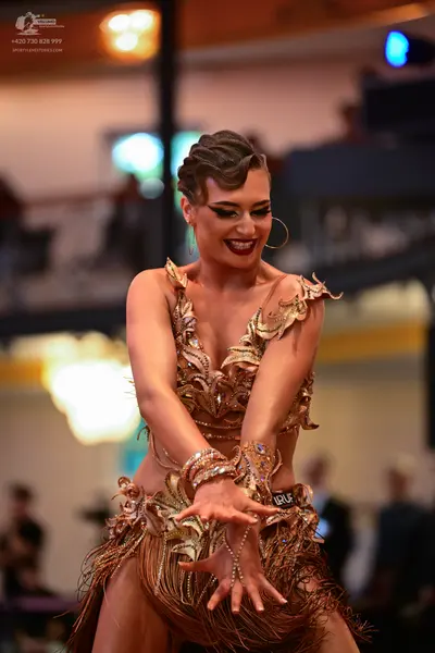 Dancesport competitor: Female dancer: gold and bronze Latin dance costume with heavy sequin and bead em
