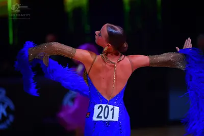 Dancesport competitor: Female dancer: blue sequined Latin dress with long, sheer, nude-colored sleeves 