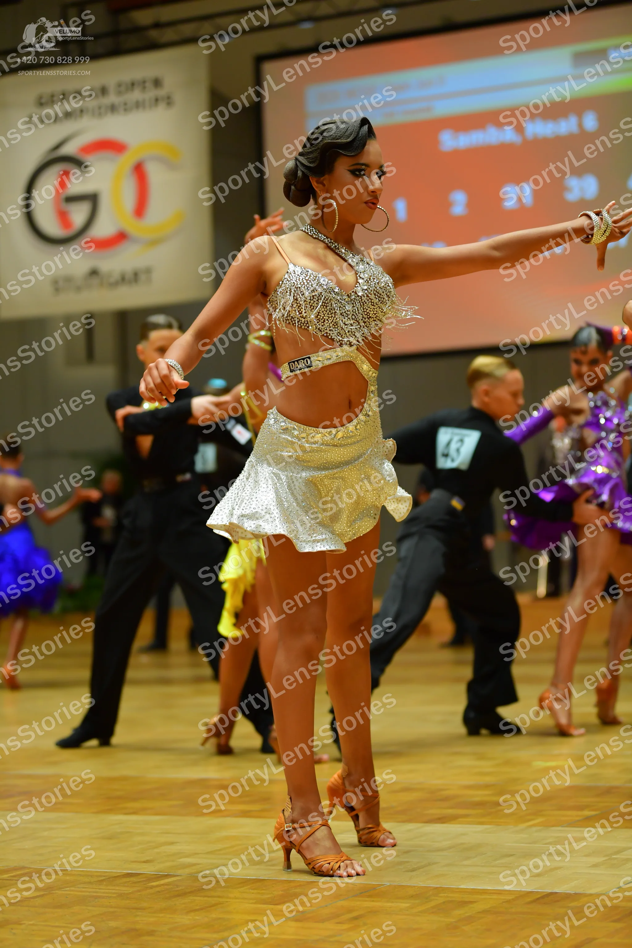 Dancesport competitor: Female dancer (foreground): silver sequin latin dress with large gold hoop earri