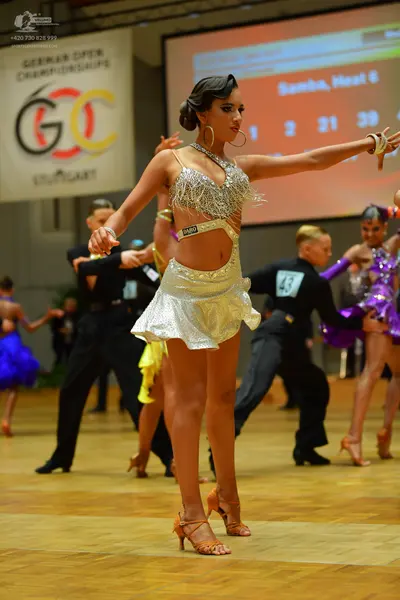 Dancesport competitor: Female dancer (foreground): silver sequin latin dress with large gold hoop earri