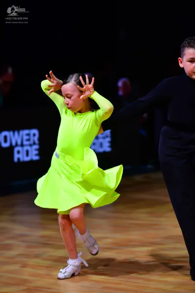 Dancesport competitor: Female dancer: neon yellow long-sleeved Latin dress with a ruffled skirt