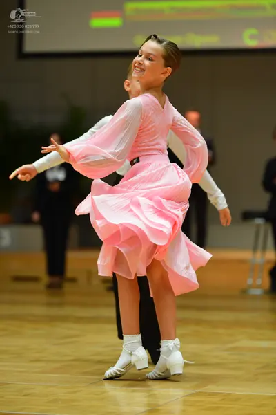 Dancesport competitor: Female dancer: pink long-sleeved ballroom dress with sheer, puffy sleeves and a 