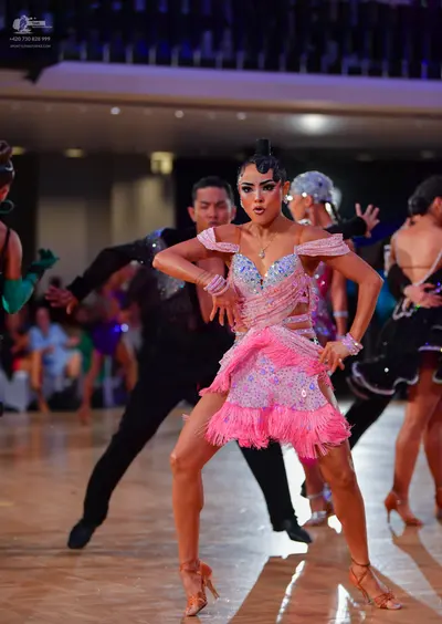 Dancesport competitor: Female dancer: pink Latin dance dress with sequins, crystals, fringe, and off-th