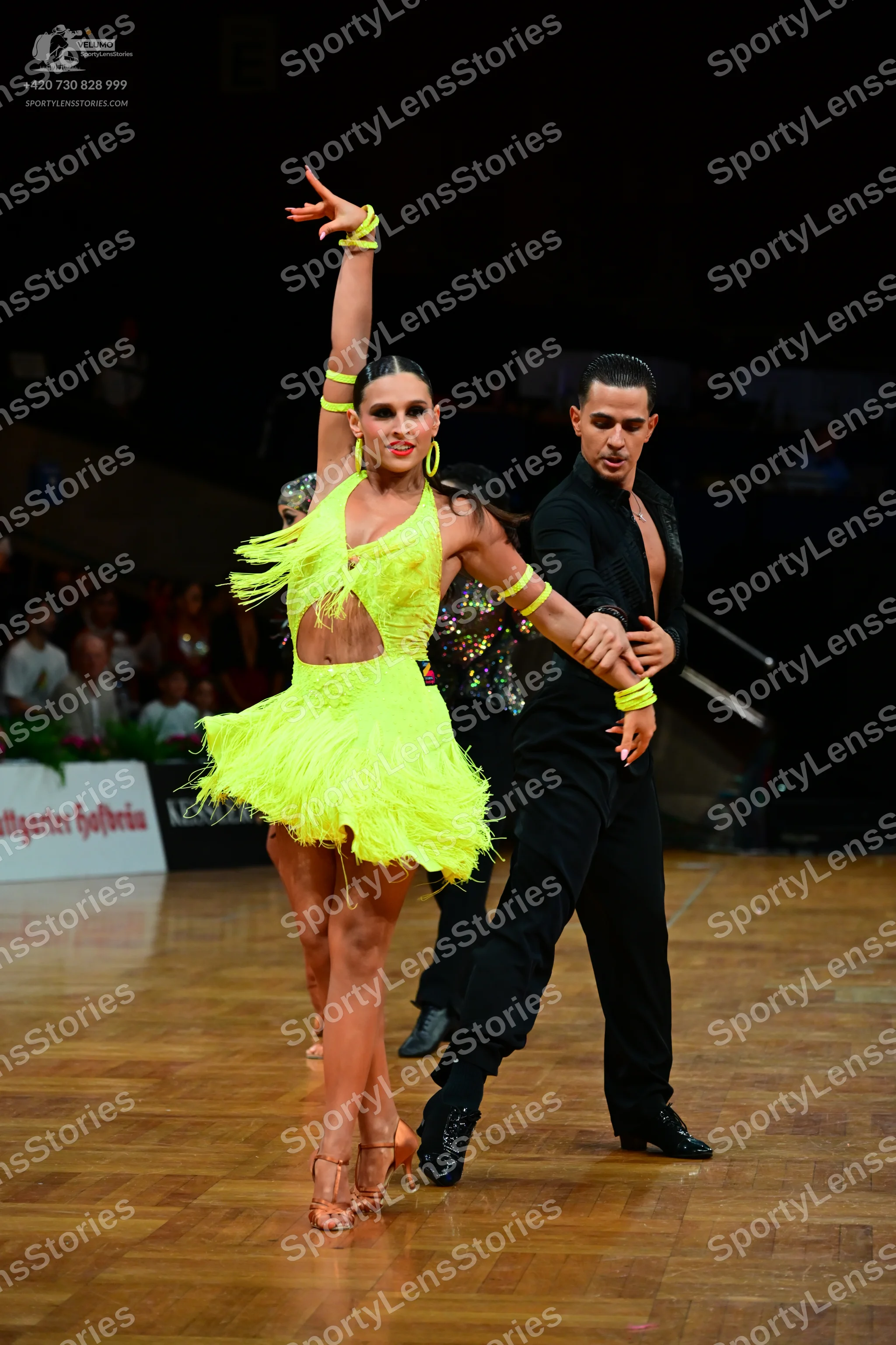 Dancesport competitor: Female dancer: neon yellow Latin dress with fringe and cutouts, matching neon ye