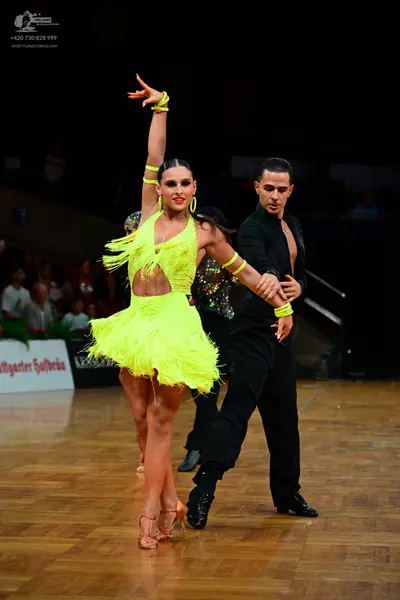Dancesport competitor: Female dancer: neon yellow Latin dress with fringe and cutouts, matching neon ye