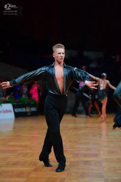 Dancesport competitor: Male dancer: dark, possibly black or charcoal, long-sleeved shirt with subtle se