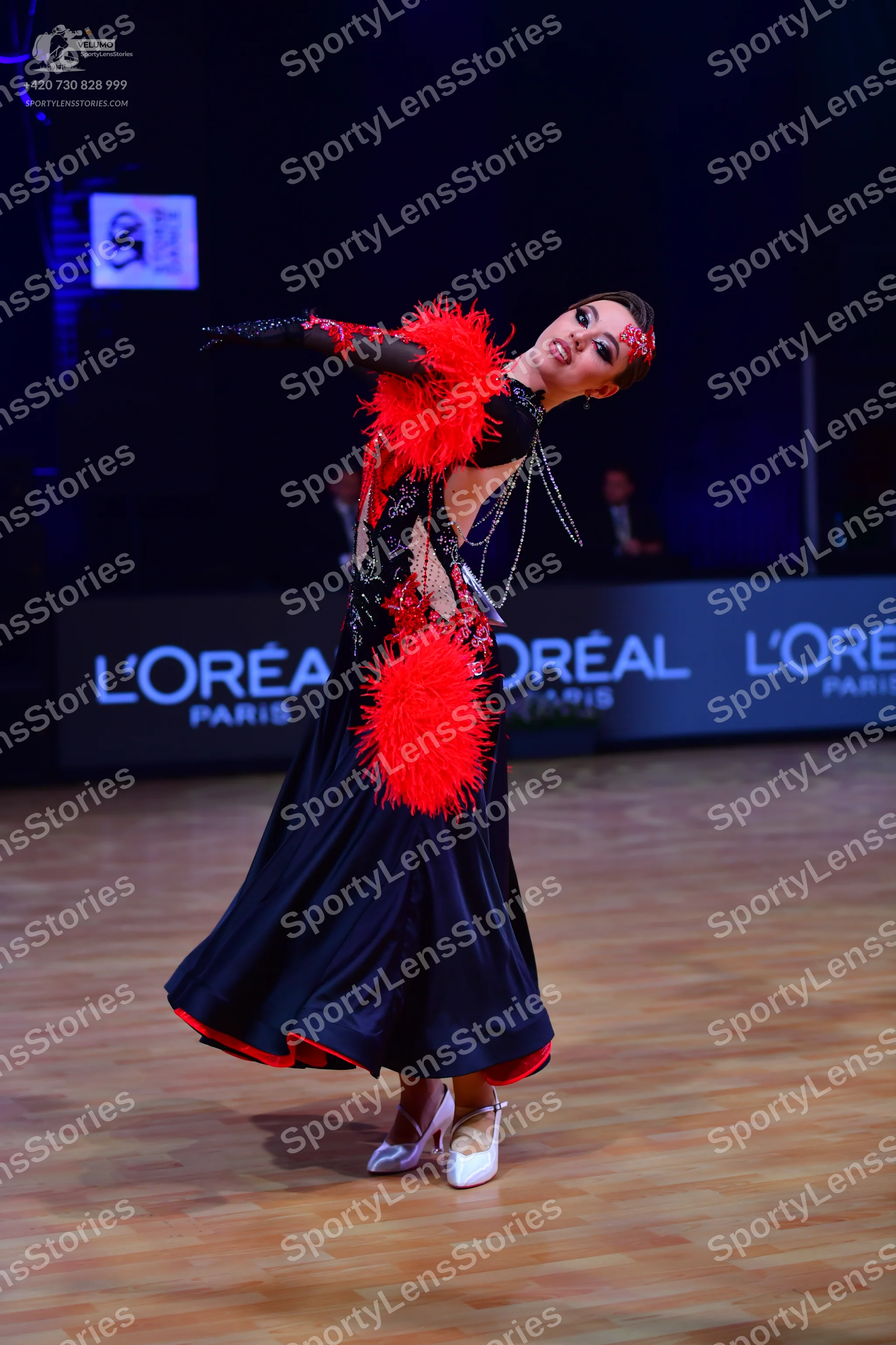 Dancesport competitor: Female dancer: dark navy or black long ballroom dress with large red feathery em