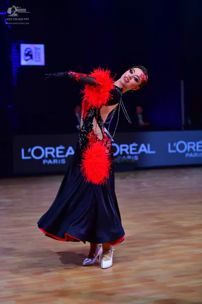 Dancesport competitor: Female dancer: dark navy or black long ballroom dress with large red feathery em