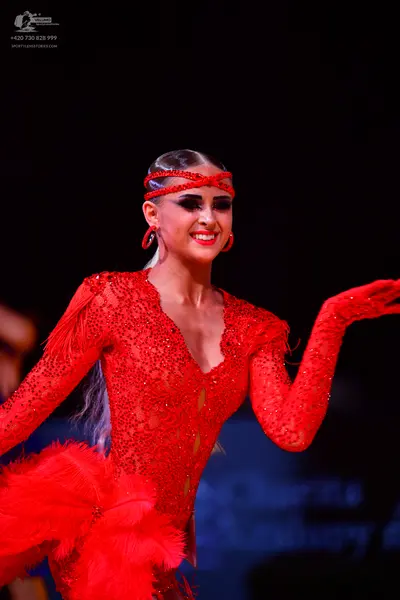 Dancesport competitor: Female dancer: red latin dress with sequins, long sleeves, and red feathers