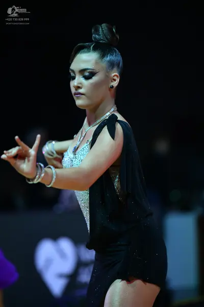 Dancesport competitor: Female dancer: black latin dress with a white/silver sequined bodice and a flowi