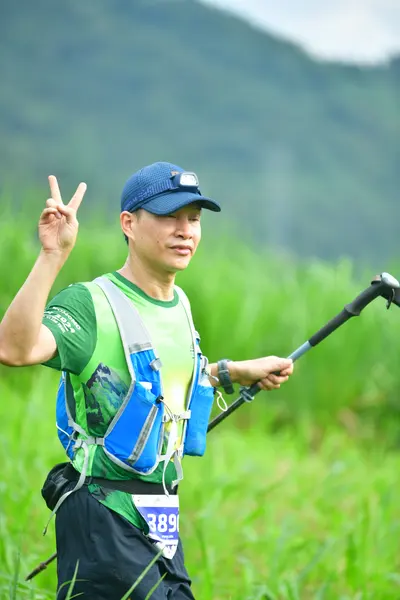 Marathon runner #389: Runner 1: green and white patterned tank top, blue hydration vest, black shorts,