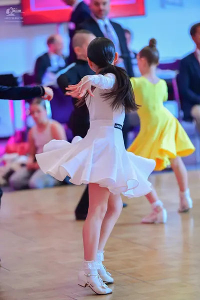 Dancesport competitor: Female dancer: white long-sleeved dress with a voluminous, multi-layered flared 