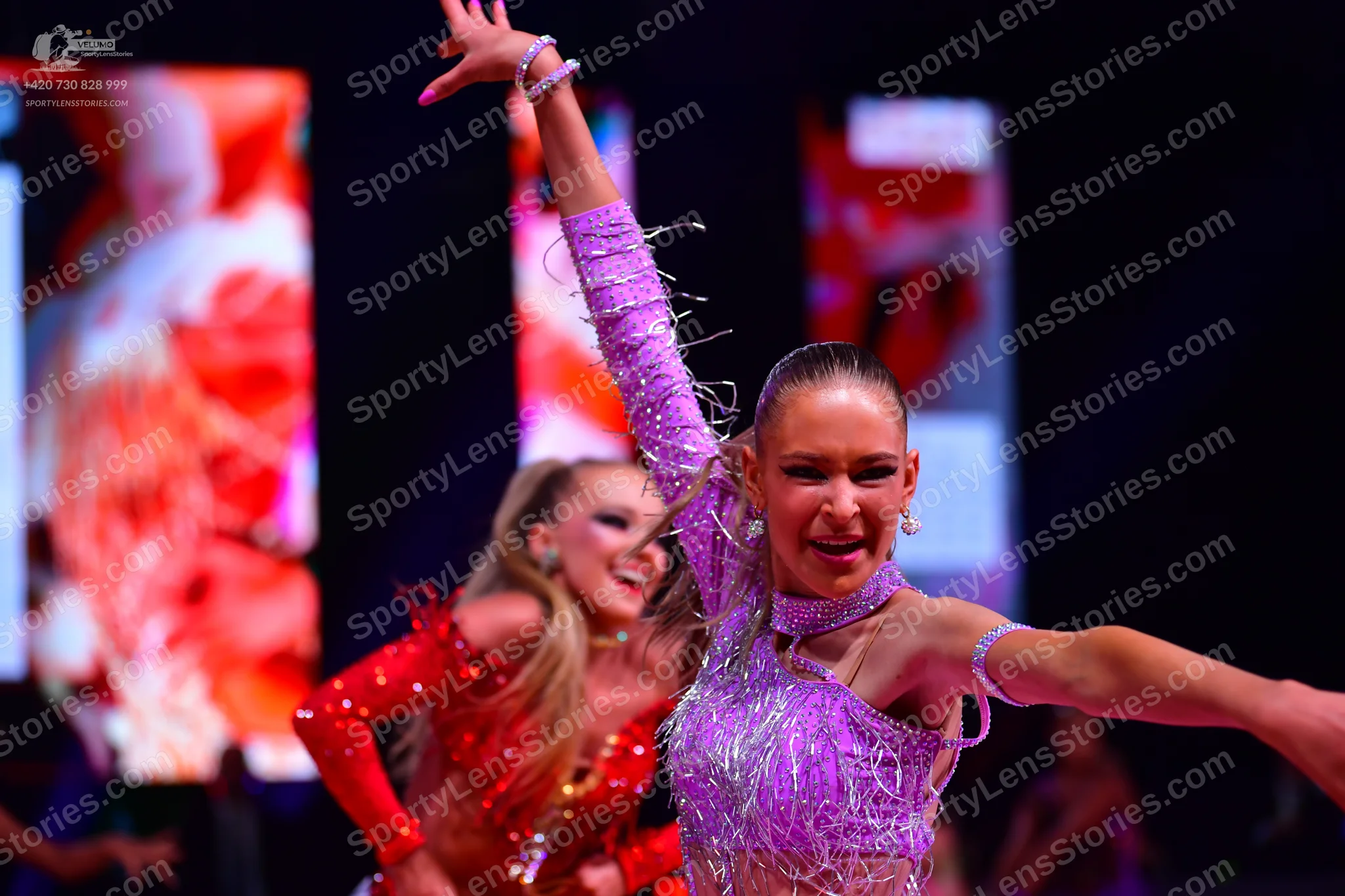 Dancesport competitor: Female dancer in foreground: light purple/lavender Latin dress with sequins and 