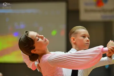 Dancesport competitor: Female dancer: light pink long-sleeved dress with a textured/lace bodice and ple