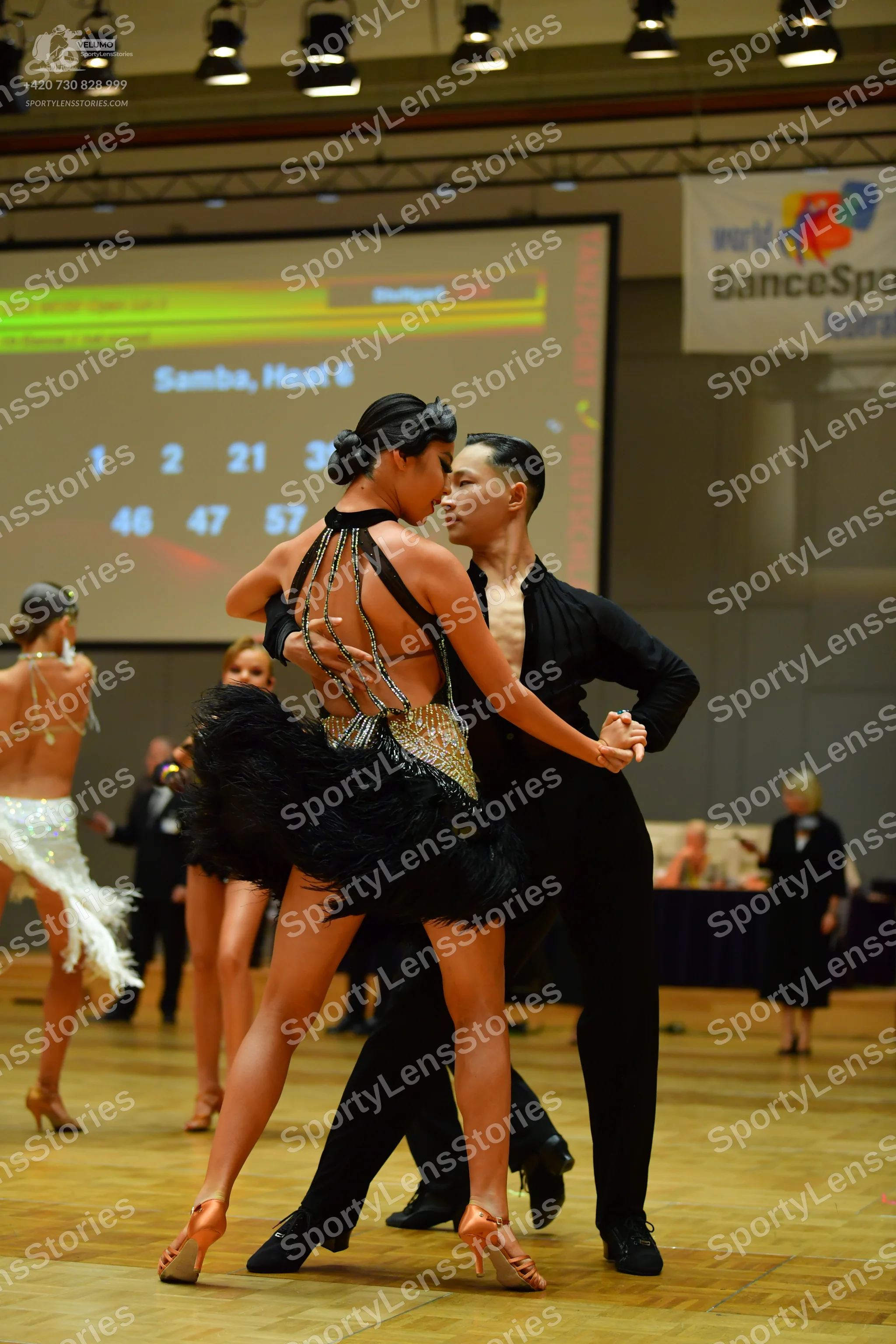 Dancesport competitor: Main female dancer: black Latin dance dress with a feathered skirt and sequin em