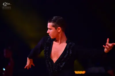 Dancesport competitor: Male dancer: black long-sleeved top with a deep V-neckline and textured or sequi