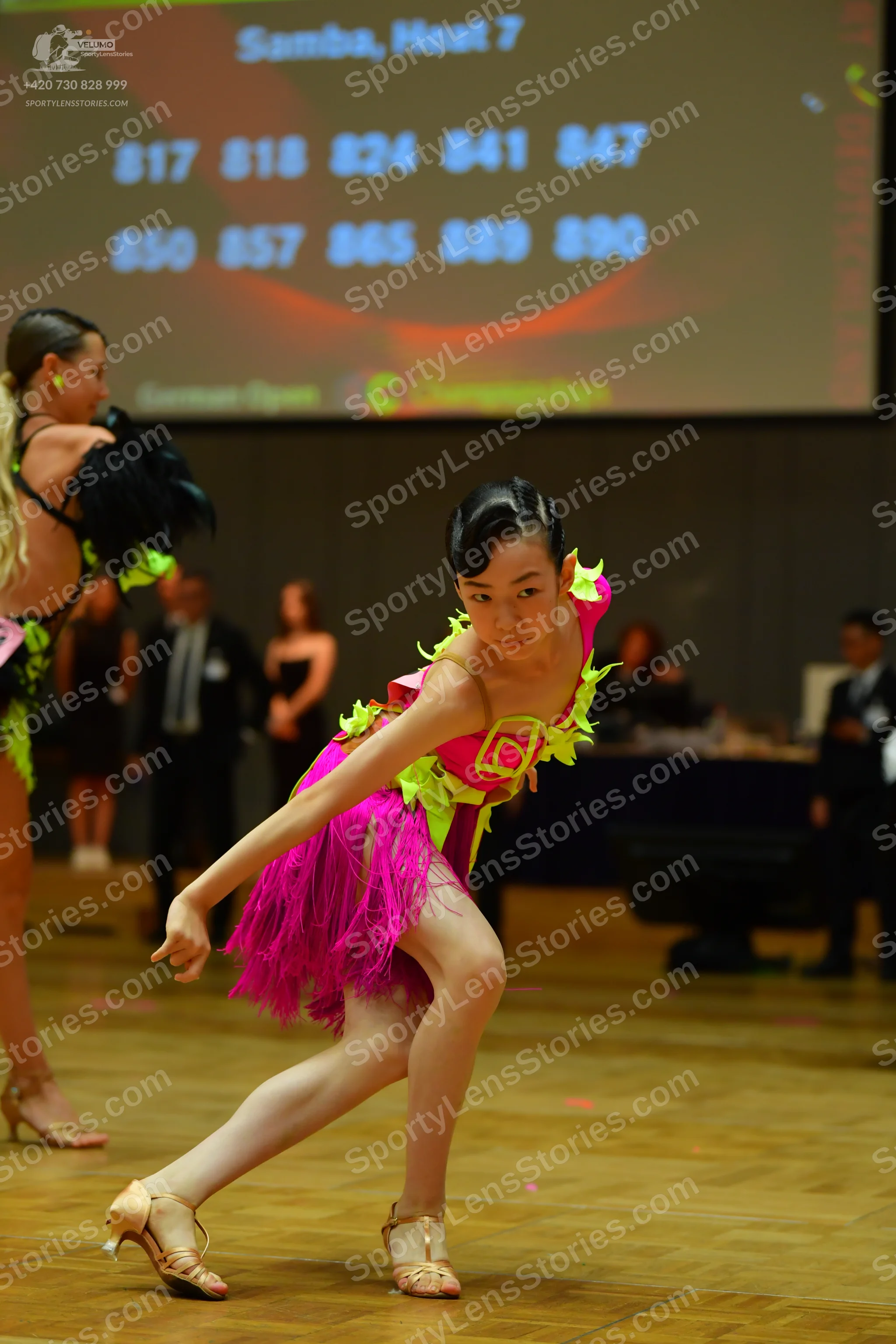 Dancesport competitor: Female dancer (left): black latin dress with lime green accents and black feathe