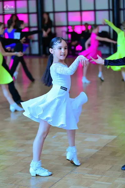 Dancesport competitor: Foreground dancer: white latin dress with a lace long-sleeved bodice and a flare