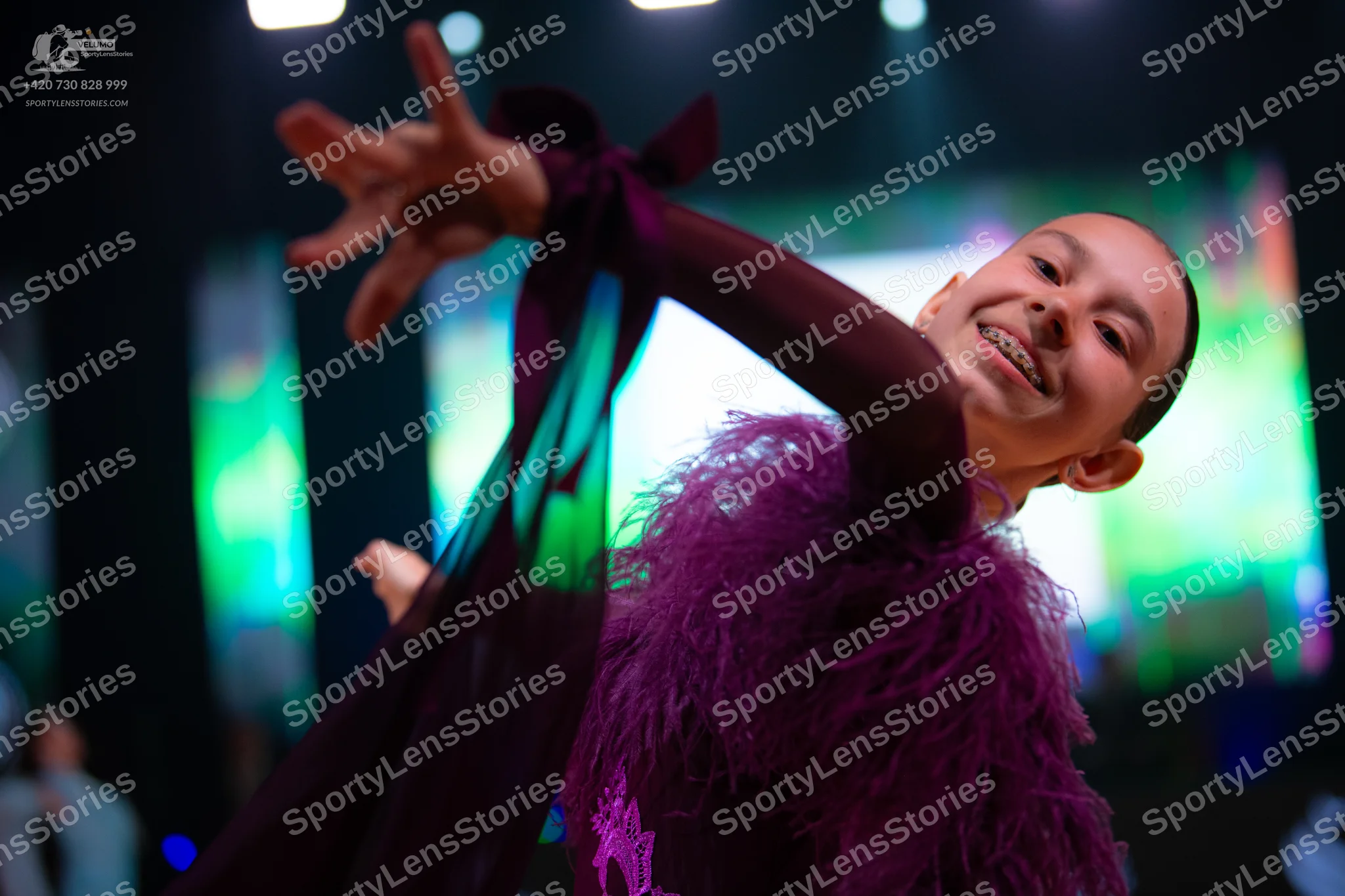 Dancesport competitor: Female dancer: dark purple/plum colored costume with feather or heavy fringe emb