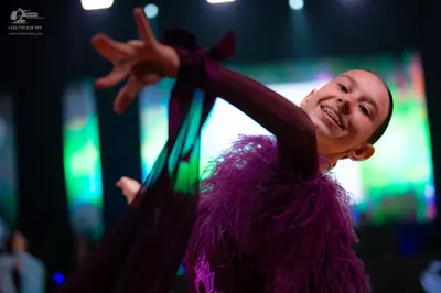 Dancesport competitor: Female dancer: dark purple/plum colored costume with feather or heavy fringe emb
