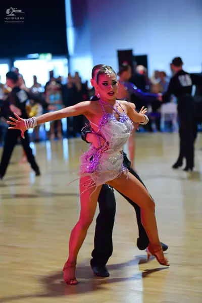Dancesport competitor: Female dancer: white and silver sequined Latin dance dress with fringe and a plu