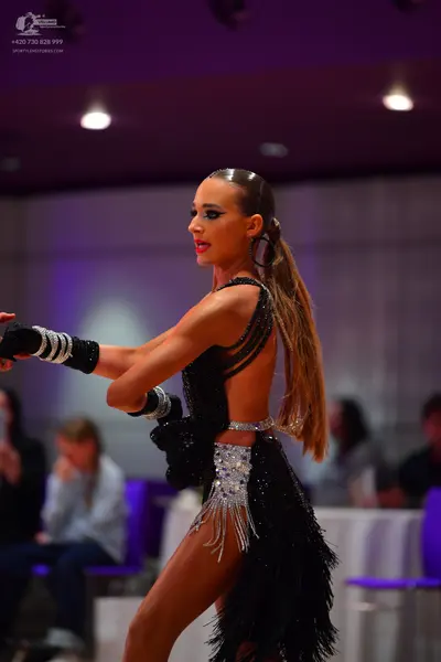 Dancesport competitor: Female dancer: black latin dress with sequins, rhinestones, and fringe, includin