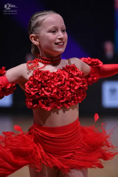 Dancesport competitor: Female dancer: red latin dress with 3D floral rose top, long sleeves, and feathe
