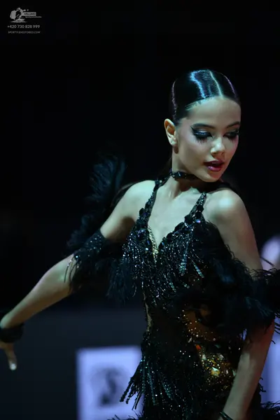 Dancesport competitor: Female dancer: black latin dress with sequins, feathers, and a deep V-neckline, 