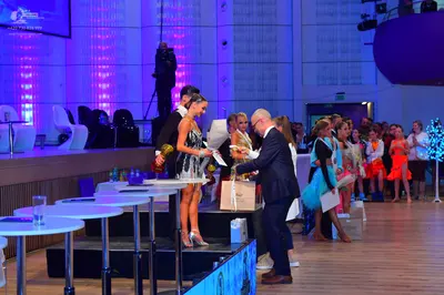 Dancesport competitor: Female dancer in foreground: short black/dark grey Latin dress with sequins