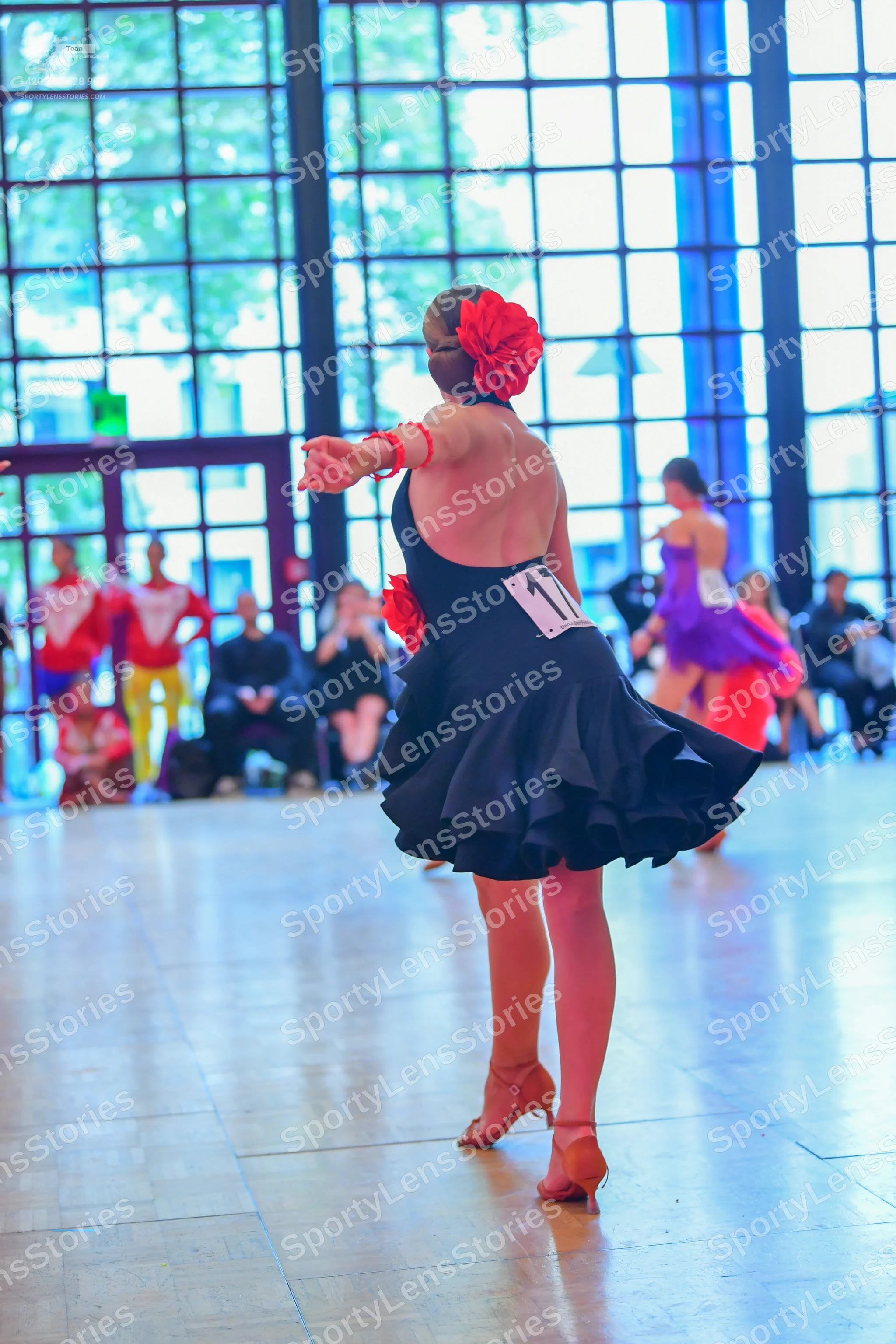 Dancesport competitor #11: Female dancer in foreground: black latin dress with a ruffled skirt and a low ba
