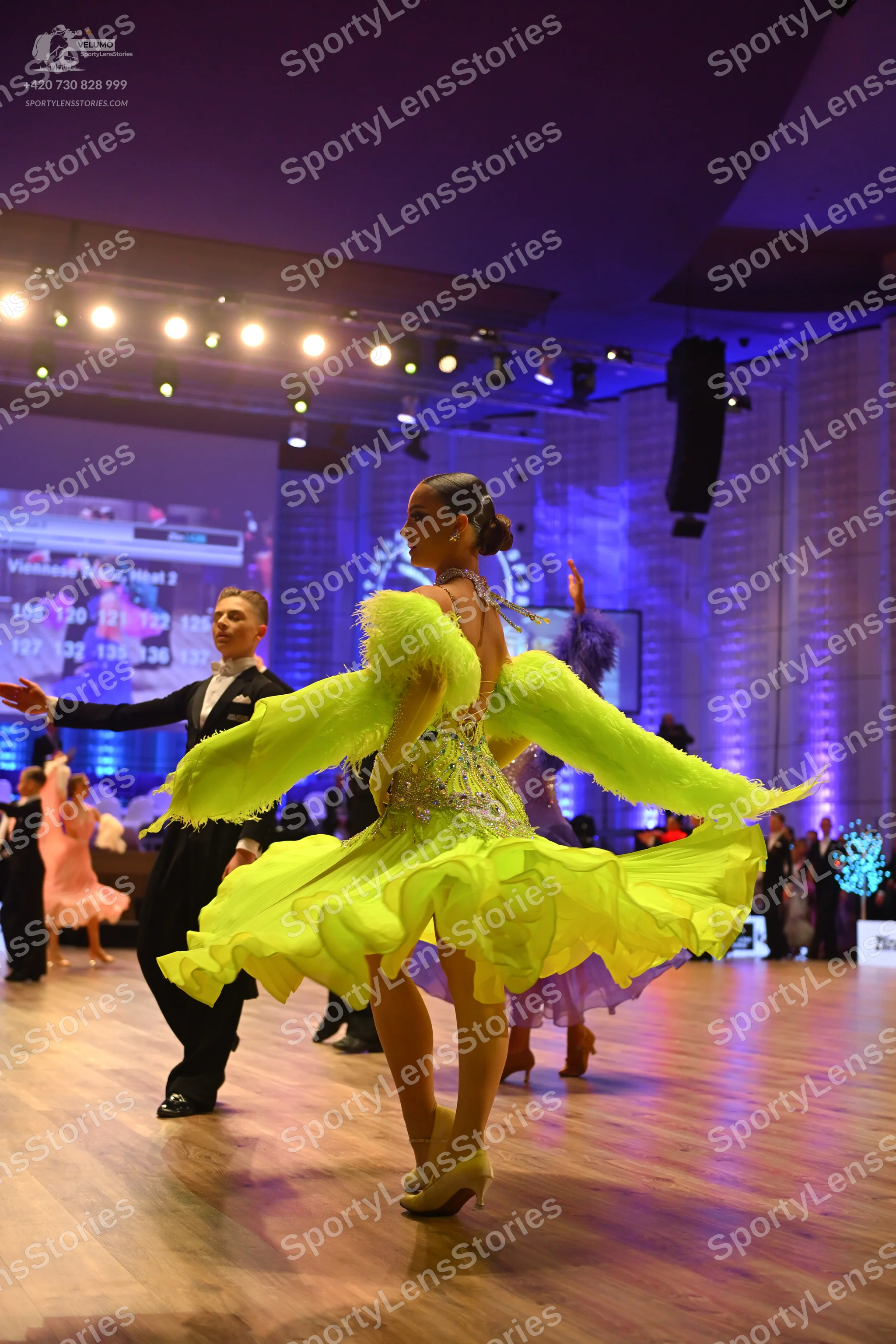 Dancesport competitor: Female dancer in foreground: lime green latin dress with a voluminous ruffled sk