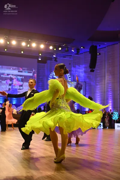 Dancesport competitor: Female dancer in foreground: lime green latin dress with a voluminous ruffled sk