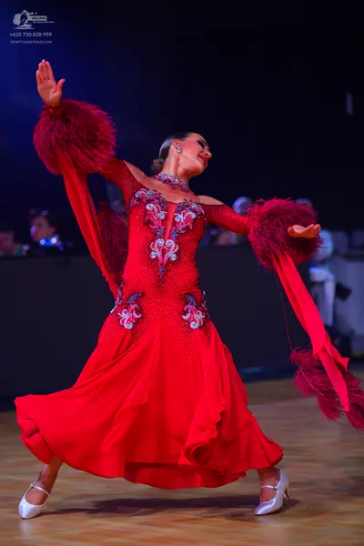 Dancesport competitor: Female dancer: red long flowing dress with silver, blue, and white sequin/beadwo