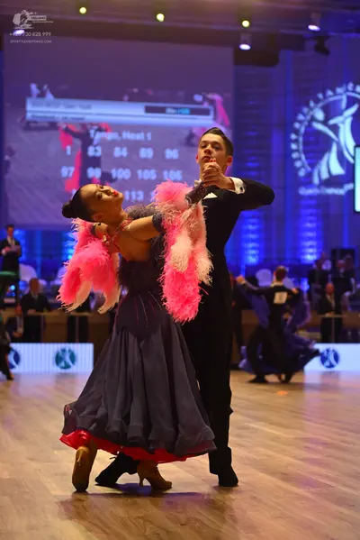 Dancesport competitor: Female dancer: dark navy ballroom dress with a voluminous bright pink feathered 