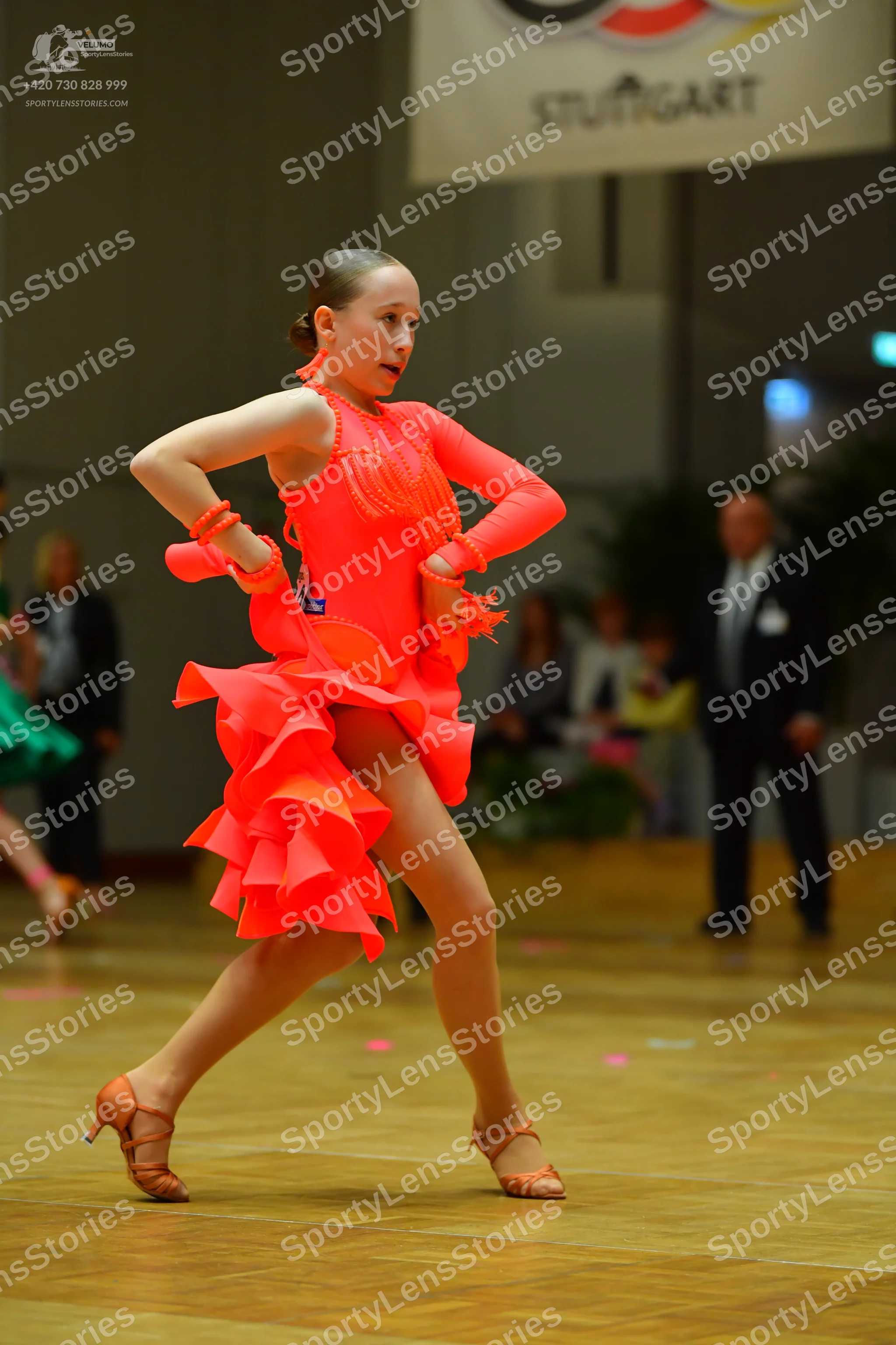 Dancesport competitor: Female dancer: bright orange latin dress with a multi-layered ruffled skirt and
