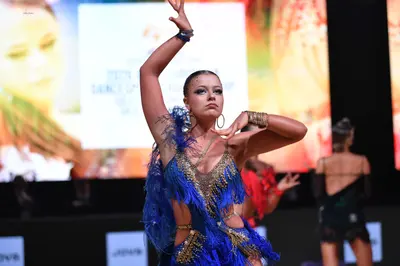 Dancesport competitor: Main female dancer: blue and gold Latin dance dress featuring heavy blue fringe 