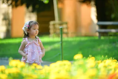 Dancesport competitor: The child is wearing a pink patterned sleeveless dress and a white lace headband