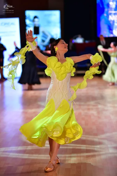 Dancesport competitor: Female dancer in center: white bodice with a voluminous, ruffled lime green skir