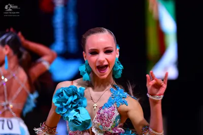 Dancesport competitor: Female dancer in foreground: blue and pink latin dance dress with heavy sequin a